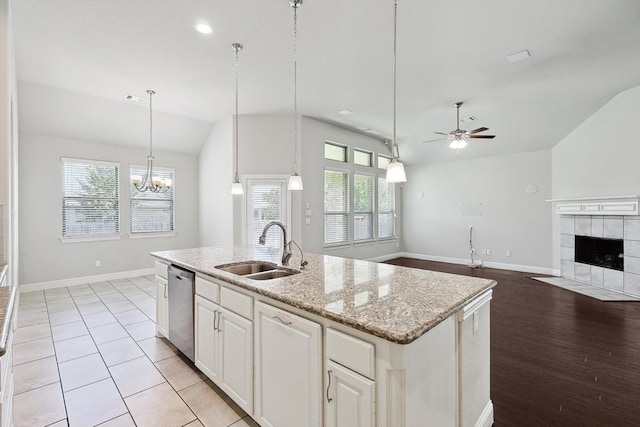 kitchen featuring an island with sink, sink, stainless steel dishwasher, and decorative light fixtures