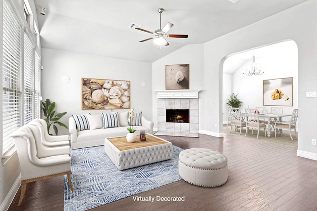 living room with dark hardwood / wood-style flooring, ceiling fan with notable chandelier, lofted ceiling, and a tile fireplace