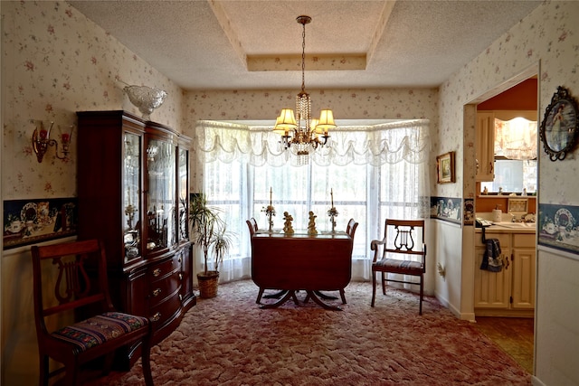 carpeted dining space with a tray ceiling, a chandelier, and a textured ceiling