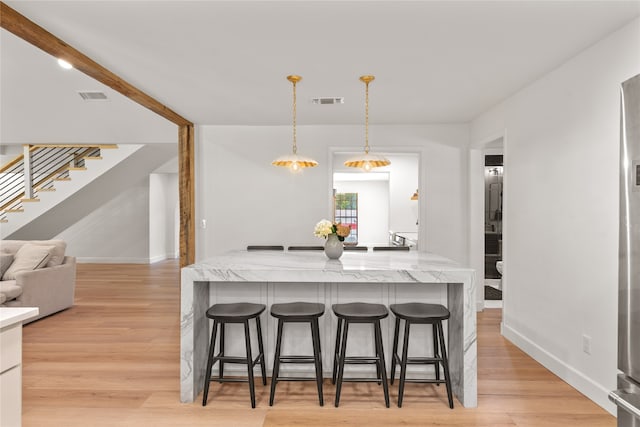 kitchen with pendant lighting, light hardwood / wood-style floors, and a breakfast bar area