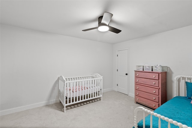 carpeted bedroom with a nursery area and ceiling fan