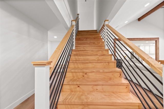 stairway with vaulted ceiling with beams and hardwood / wood-style floors