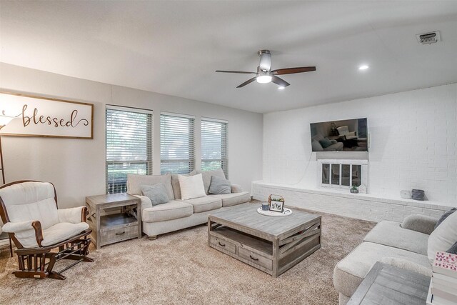 living room featuring ceiling fan, light colored carpet, and a fireplace