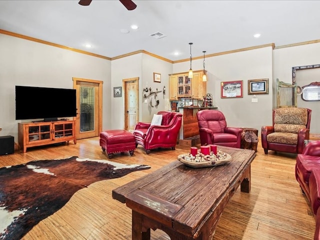 living room featuring ceiling fan, ornamental molding, and light hardwood / wood-style flooring