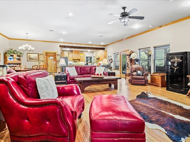 living room with hardwood / wood-style flooring, crown molding, and ceiling fan with notable chandelier