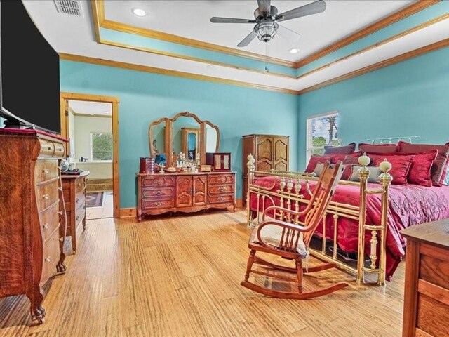 bedroom featuring ceiling fan, a raised ceiling, crown molding, and wood-type flooring