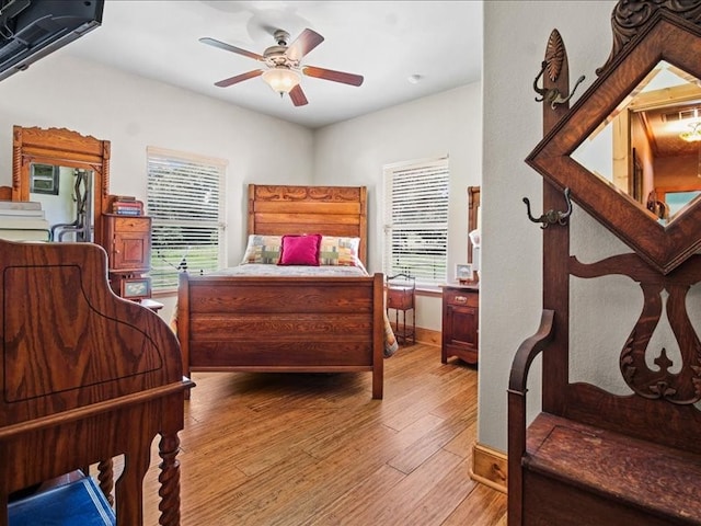 bedroom with hardwood / wood-style floors, ceiling fan, and multiple windows