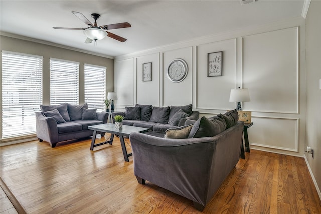 living room featuring wood-type flooring, ceiling fan, and crown molding