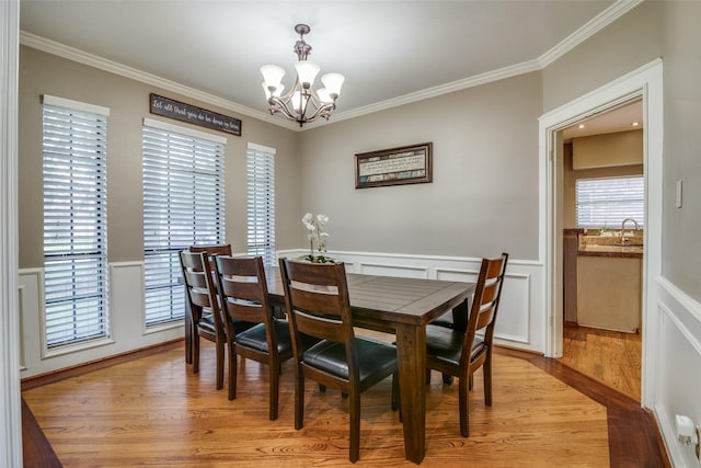 dining space featuring an inviting chandelier, sink, crown molding, and light hardwood / wood-style flooring