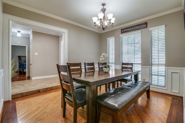 dining area featuring ornamental molding, light hardwood / wood-style floors, and a notable chandelier