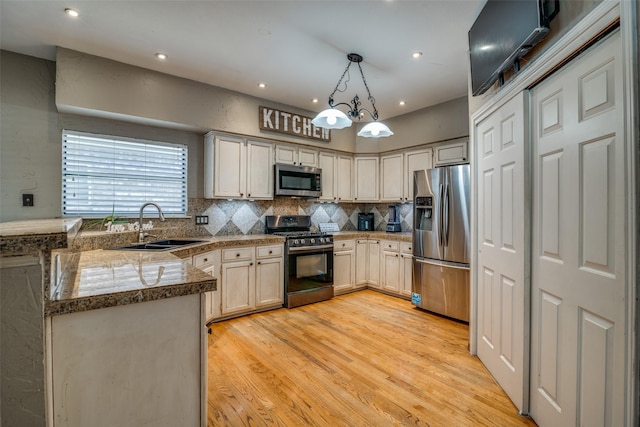 kitchen with sink, kitchen peninsula, stainless steel appliances, and light wood-type flooring