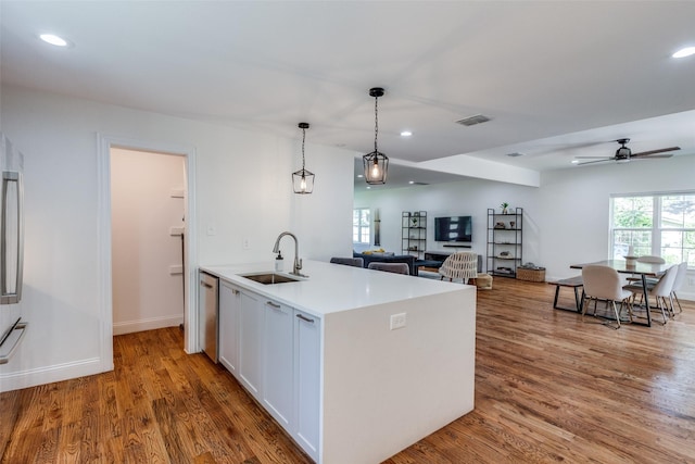 kitchen with sink, pendant lighting, light hardwood / wood-style floors, a kitchen island with sink, and white cabinets