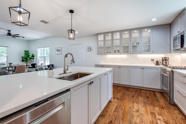 kitchen with ceiling fan, sink, stainless steel appliances, and decorative light fixtures