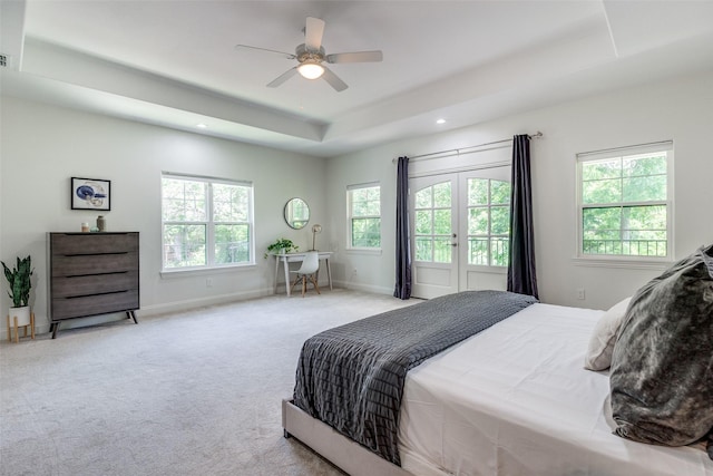 bedroom with a raised ceiling, multiple windows, ceiling fan, and light carpet