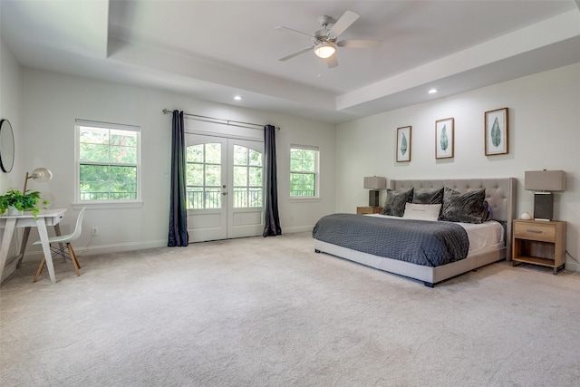 carpeted bedroom with a tray ceiling, access to exterior, ceiling fan, and french doors