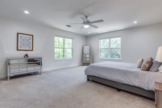 bedroom with ceiling fan, light carpet, and multiple windows