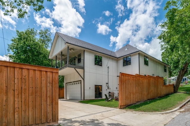 view of front of house featuring a front yard, a balcony, a garage, and ceiling fan