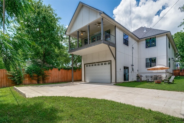 view of front of house with ceiling fan, a balcony, a front yard, and a garage