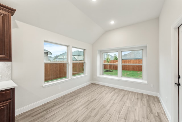 unfurnished dining area with vaulted ceiling and light hardwood / wood-style flooring