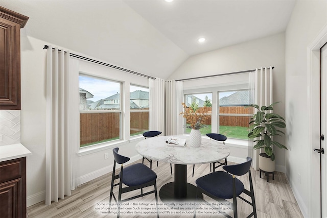 dining area featuring vaulted ceiling and light hardwood / wood-style flooring