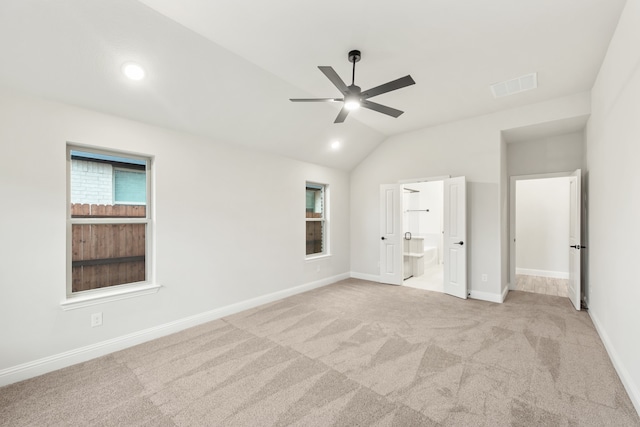 unfurnished bedroom with vaulted ceiling, light carpet, ensuite bath, and ceiling fan