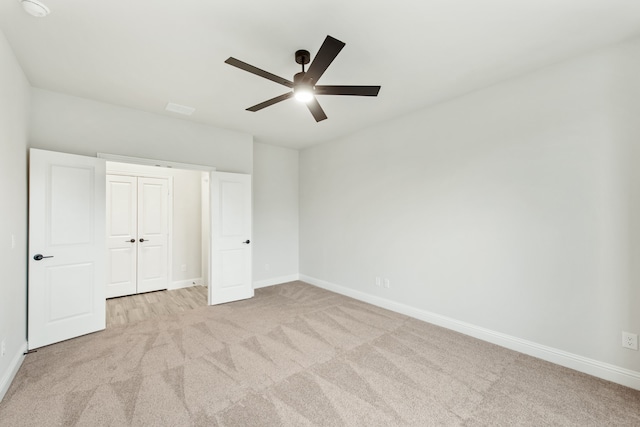 unfurnished bedroom with light colored carpet, ceiling fan, and a closet