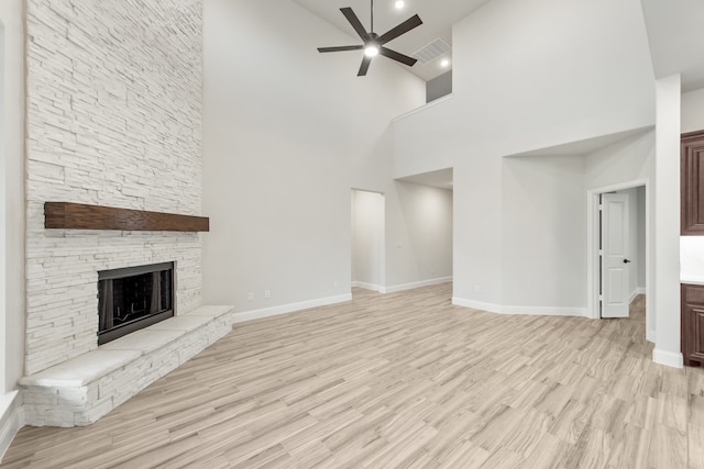 unfurnished living room featuring high vaulted ceiling, light hardwood / wood-style flooring, ceiling fan, and a stone fireplace