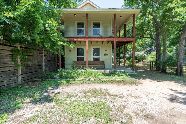 back of property featuring covered porch and a balcony