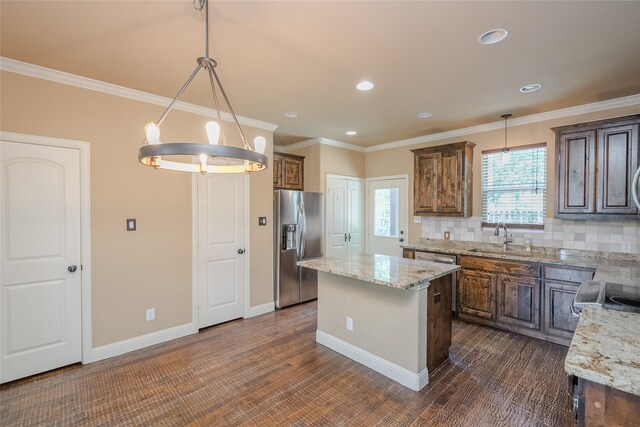 kitchen with stainless steel fridge, pendant lighting, backsplash, a center island, and sink