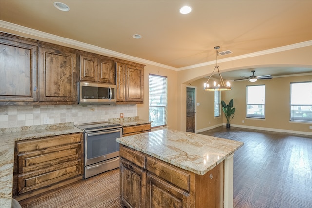 kitchen featuring light stone countertops, ceiling fan with notable chandelier, appliances with stainless steel finishes, backsplash, and pendant lighting