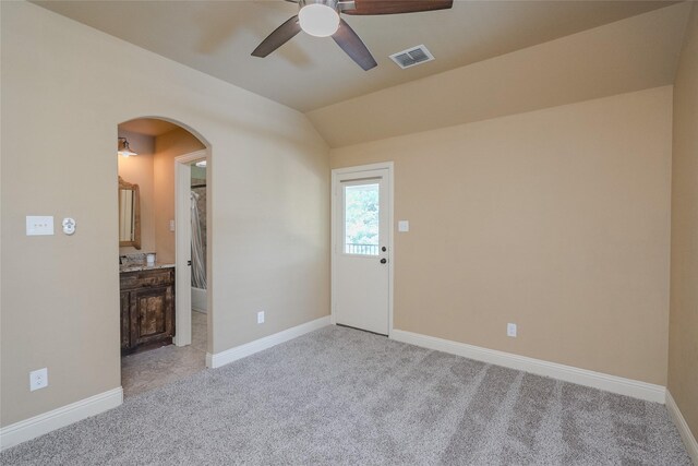 empty room with ceiling fan, vaulted ceiling, and light colored carpet