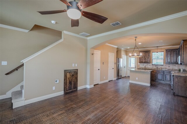 kitchen with ceiling fan with notable chandelier, stainless steel appliances, tasteful backsplash, a center island, and pendant lighting