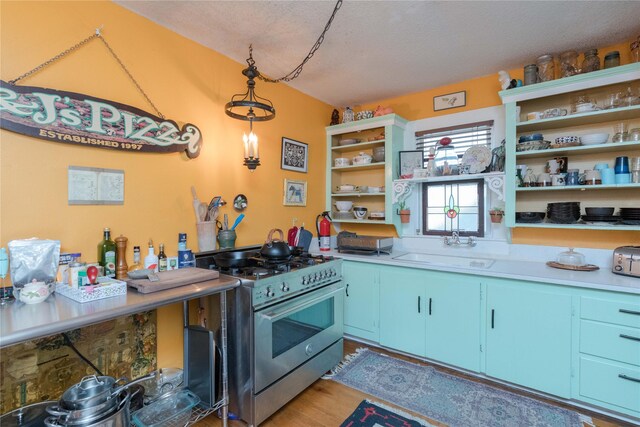 kitchen featuring light wood-type flooring, decorative light fixtures, gas range, sink, and blue cabinets