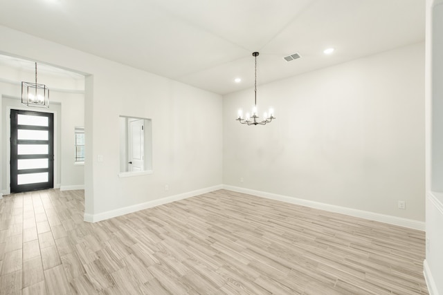 spare room featuring light hardwood / wood-style flooring and a chandelier