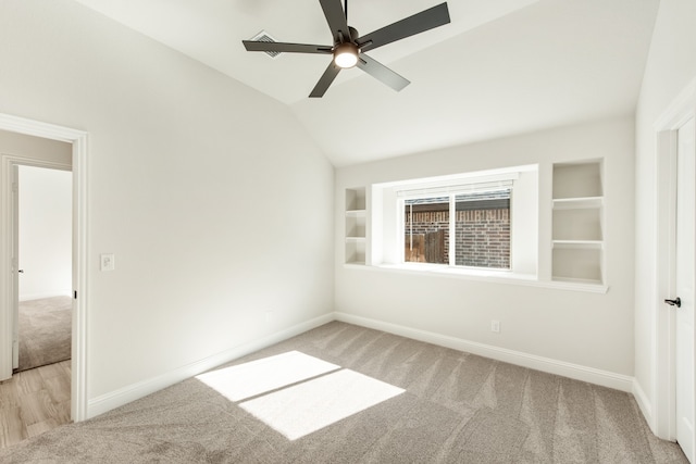 spare room featuring built in shelves, lofted ceiling, ceiling fan, and light hardwood / wood-style floors