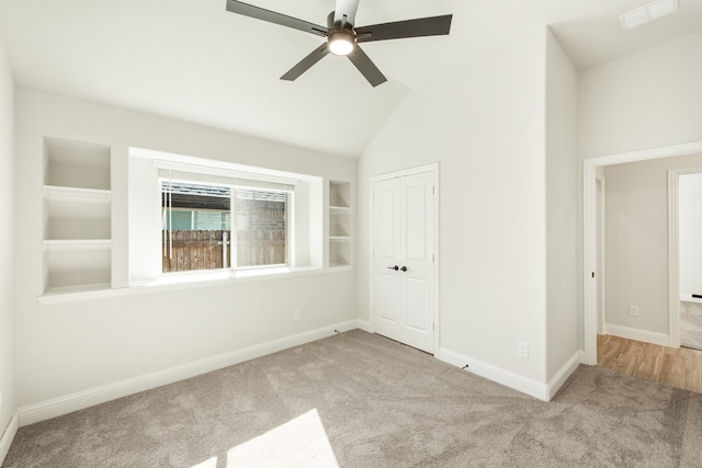 unfurnished room featuring light carpet, built in shelves, lofted ceiling, and ceiling fan