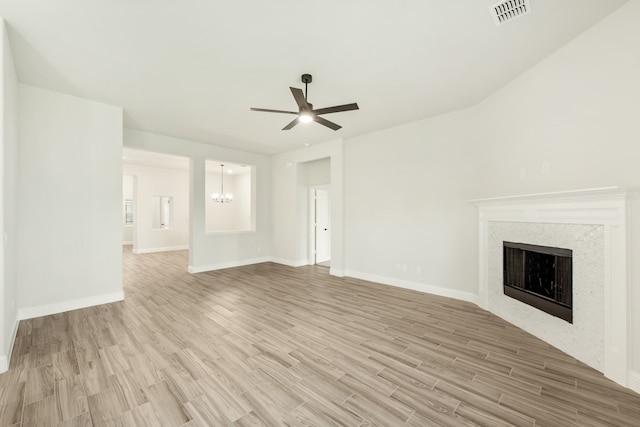 unfurnished living room with ceiling fan with notable chandelier and light hardwood / wood-style flooring