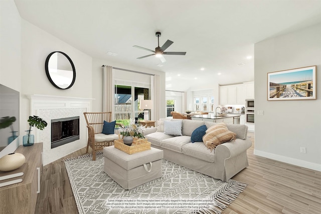 living room with light hardwood / wood-style floors, ceiling fan, and sink