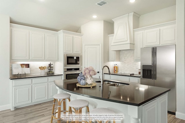 kitchen with white cabinets, sink, a center island with sink, appliances with stainless steel finishes, and decorative backsplash