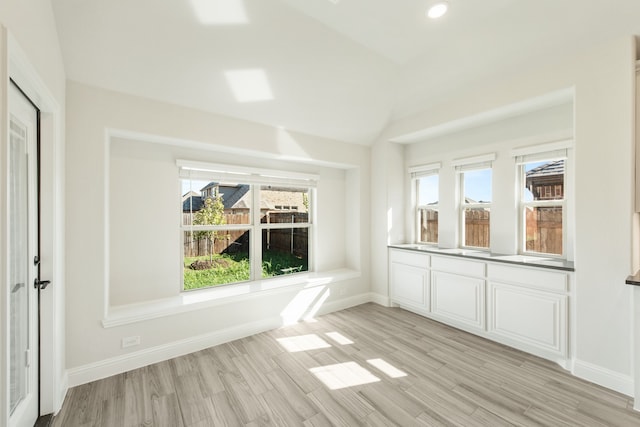 unfurnished dining area with lofted ceiling and light hardwood / wood-style floors