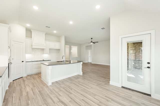 kitchen with ceiling fan, light hardwood / wood-style flooring, an island with sink, and white cabinets