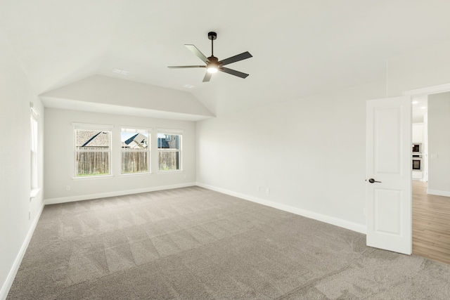 empty room with lofted ceiling, ceiling fan, and light colored carpet