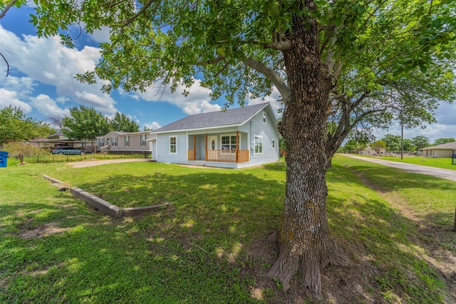 back of property featuring covered porch and a yard