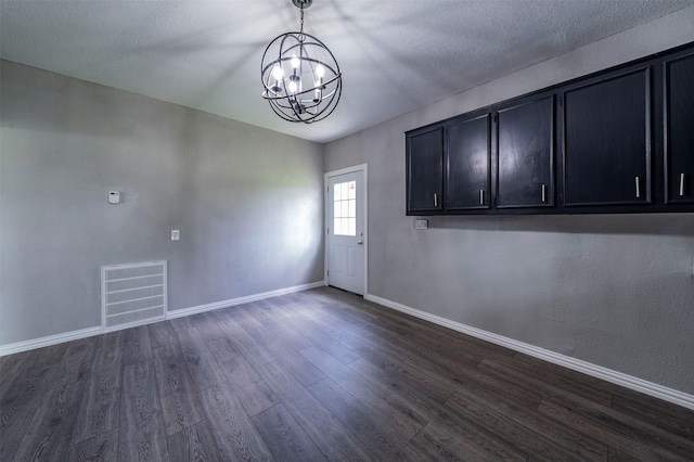 unfurnished dining area with a textured ceiling, dark hardwood / wood-style floors, and a notable chandelier