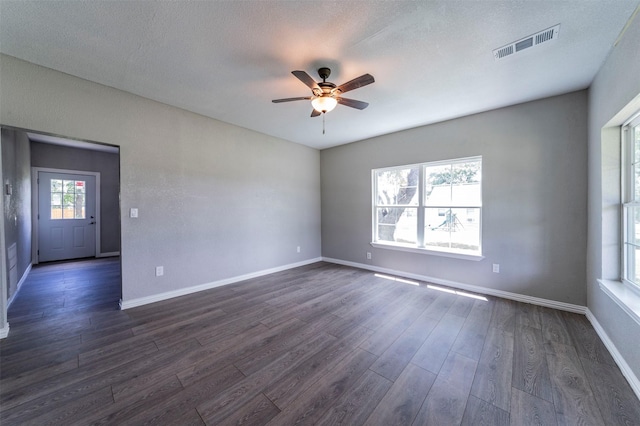 unfurnished room with a textured ceiling, ceiling fan, and dark wood-type flooring