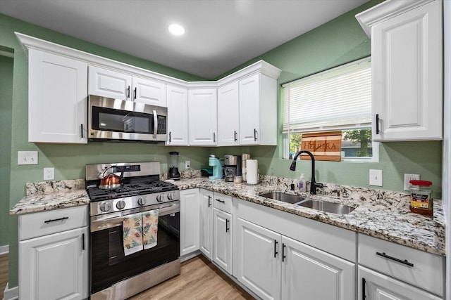 kitchen featuring white cabinets, appliances with stainless steel finishes, sink, and light hardwood / wood-style flooring