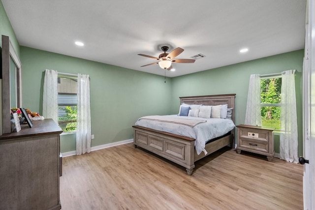 bedroom with ceiling fan, light wood-type flooring, and multiple windows