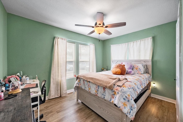 bedroom featuring ceiling fan, wood-type flooring, and a textured ceiling