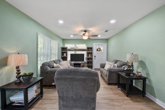 living room with ceiling fan and light hardwood / wood-style flooring