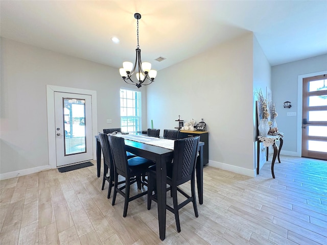 dining area with light wood-type flooring, plenty of natural light, visible vents, and a notable chandelier